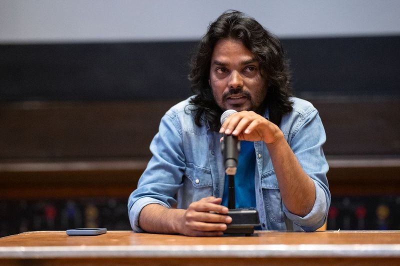 A man in a blue shirt speaks into a microphone